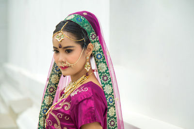 Portrait charming asian woman wearing a traditional saree with a wall background.