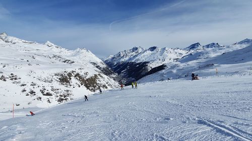 People skiing on snowcapped mountain against sky