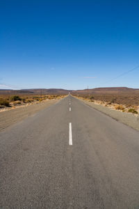 Road amidst landscape against clear blue sky