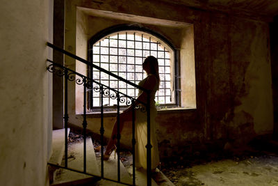 Woman standing by window in abandoned building