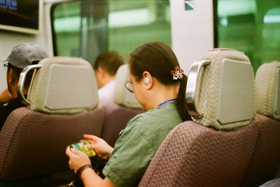 Rear view of man and woman sitting in bus