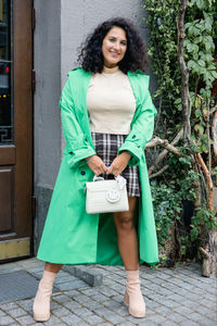 Portrait of young woman standing on footpath