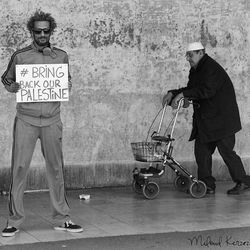 Man with umbrella standing against graffiti wall