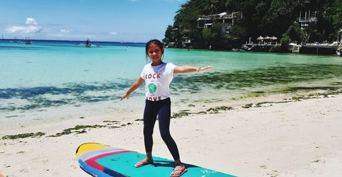 Portrait of girl standing on surfboard at beach