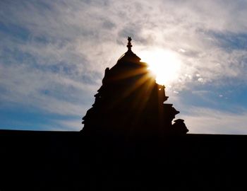 Low angle view of sun shining through clouds