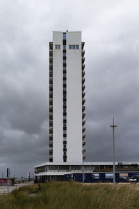 The photo shows a skyscraper on the beach of zandvoort in the netherlands with dramatic cloudy sky