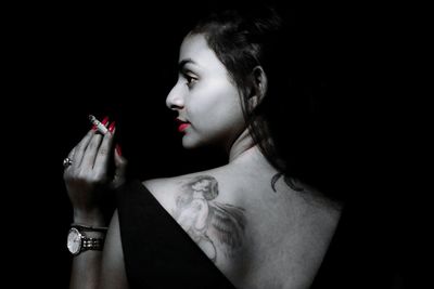 Close-up of young woman against black background