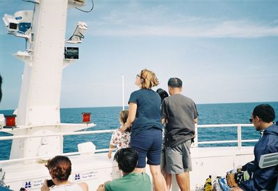 People on boat in sea against sky