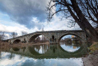 Arch bridge over river against sky