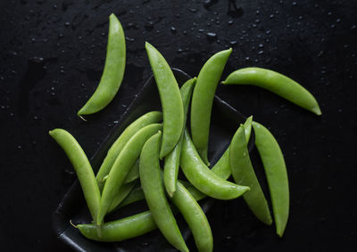 High angle view of sugar snap peas in tray on wet table