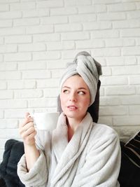 Portrait of beautiful woman drinking against wall