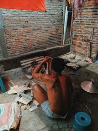 High angle view of shirtless man lying on wall