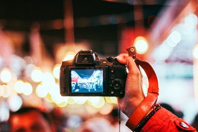 Midsection of person photographing illuminated mobile phone