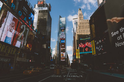 Street amidst buildings with advertisement in city against sky