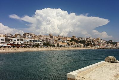 Scenic view of sea by buildings against sky