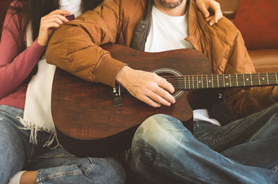 Midsection of couple playing guitar