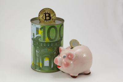 Close-up of coins in jar against white background