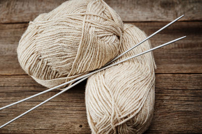 Two skeins of woolen yarn and needles for knitting on wooden background