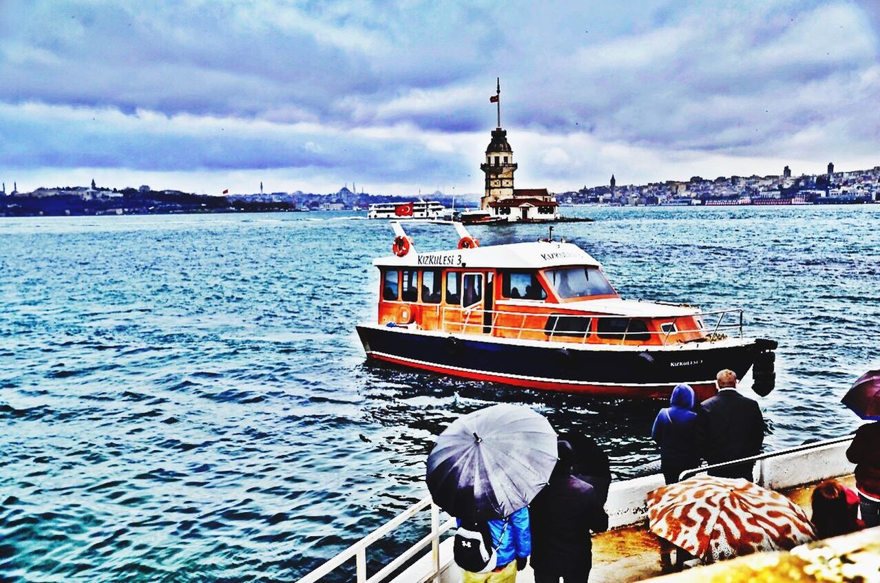 nautical vessel, water, sky, men, transportation, sea, built structure, cloud - sky, rear view, architecture, mode of transport, lifestyles, boat, leisure activity, building exterior, travel, person, cloud