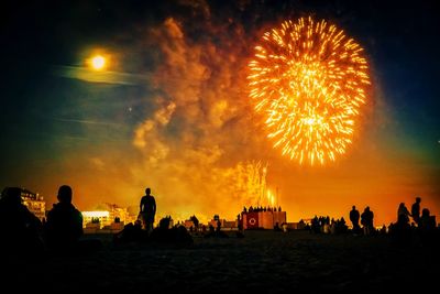 Silhouette people on beach against sky at night