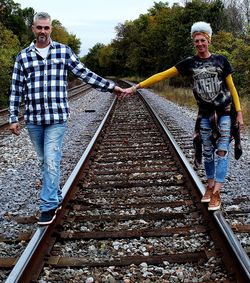 Front view of a happy couple walking on railroad track