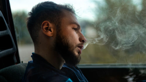 Close-up of young man looking through window