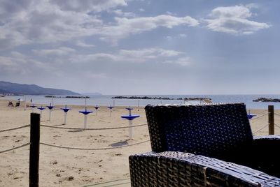 Hooded chairs on beach against sky