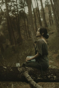 Rear view of woman sitting in forest