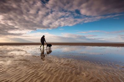 Woman on beach against sky during sunset