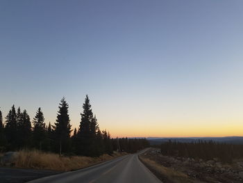 Road amidst trees against clear sky