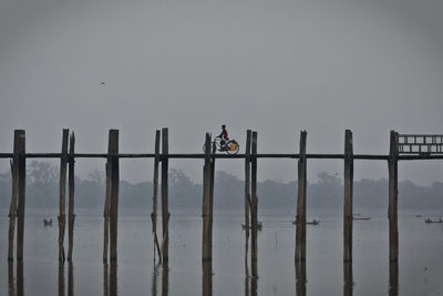 Man riding bicycle on bridge over lake