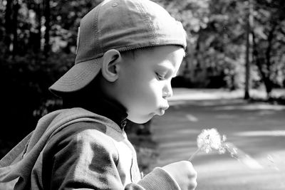 Side view of cute boy blowing dandelion seeds