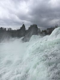 Scenic view of waterfall against cloudy sky