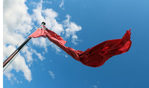 Low angle view of torn flag against blue sky