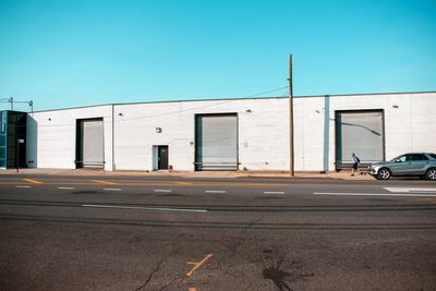 Road by building against clear blue sky