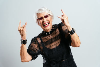 Portrait of young woman with arms raised standing against white background