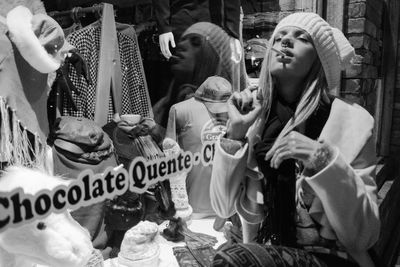 Woman smoking cigarette by window display at night