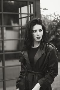 Portrait of young woman standing against fence