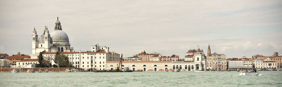 View of buildings by sea against sky in city