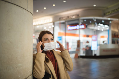 Full length portrait of woman standing against illuminated wall