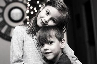 Portrait of siblings embracing while standing indoors