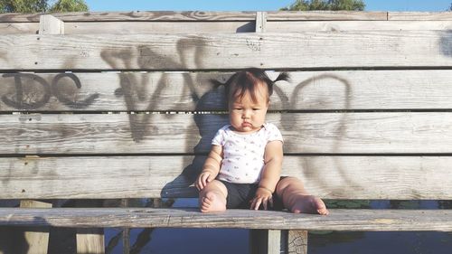 Full length portrait of girl standing against wooden wall