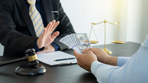 Midsection of man holding cup on table