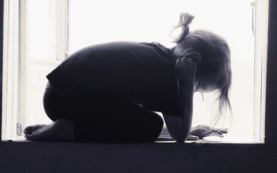 Woman sitting by window at home