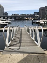 Pier over river in city against sky