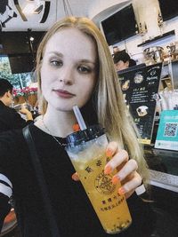 Portrait of young woman drinking drink in restaurant