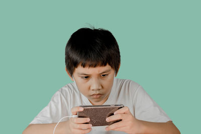 Portrait of boy holding camera against blue background