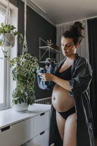 Pregnant woman folding baby clothes and getting ready for baby arrival
