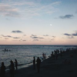 Silhouette people on beach against sky during sunset