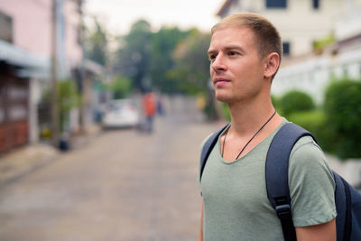 Portrait of young man standing on street in city